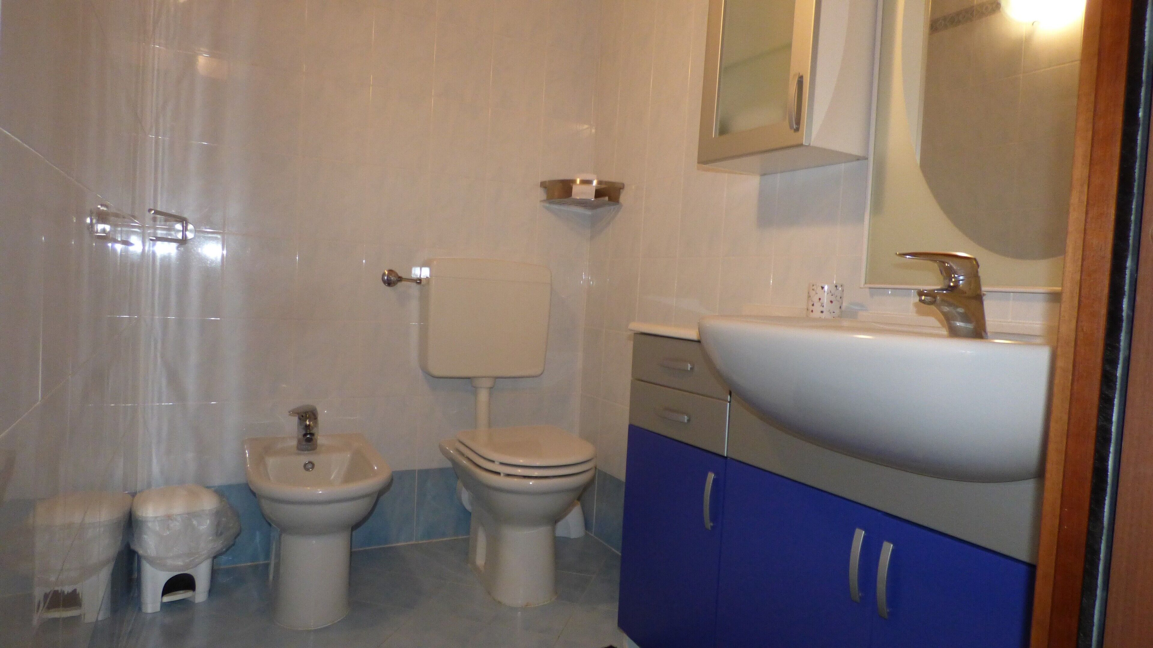 A bathroom with a toilet, bidet, sink, and mirror.