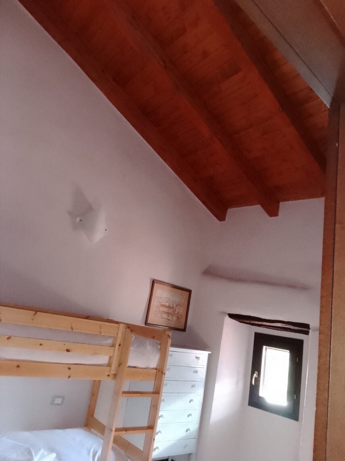 Ein Zimmer mit Etagenbett, einem Schminktisch und einem Bild an der Wand, sowie einem Fenster mit Blick.
