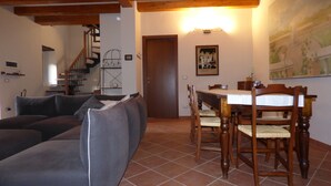 A living room with a sofa, dining table, chairs, and a staircase.