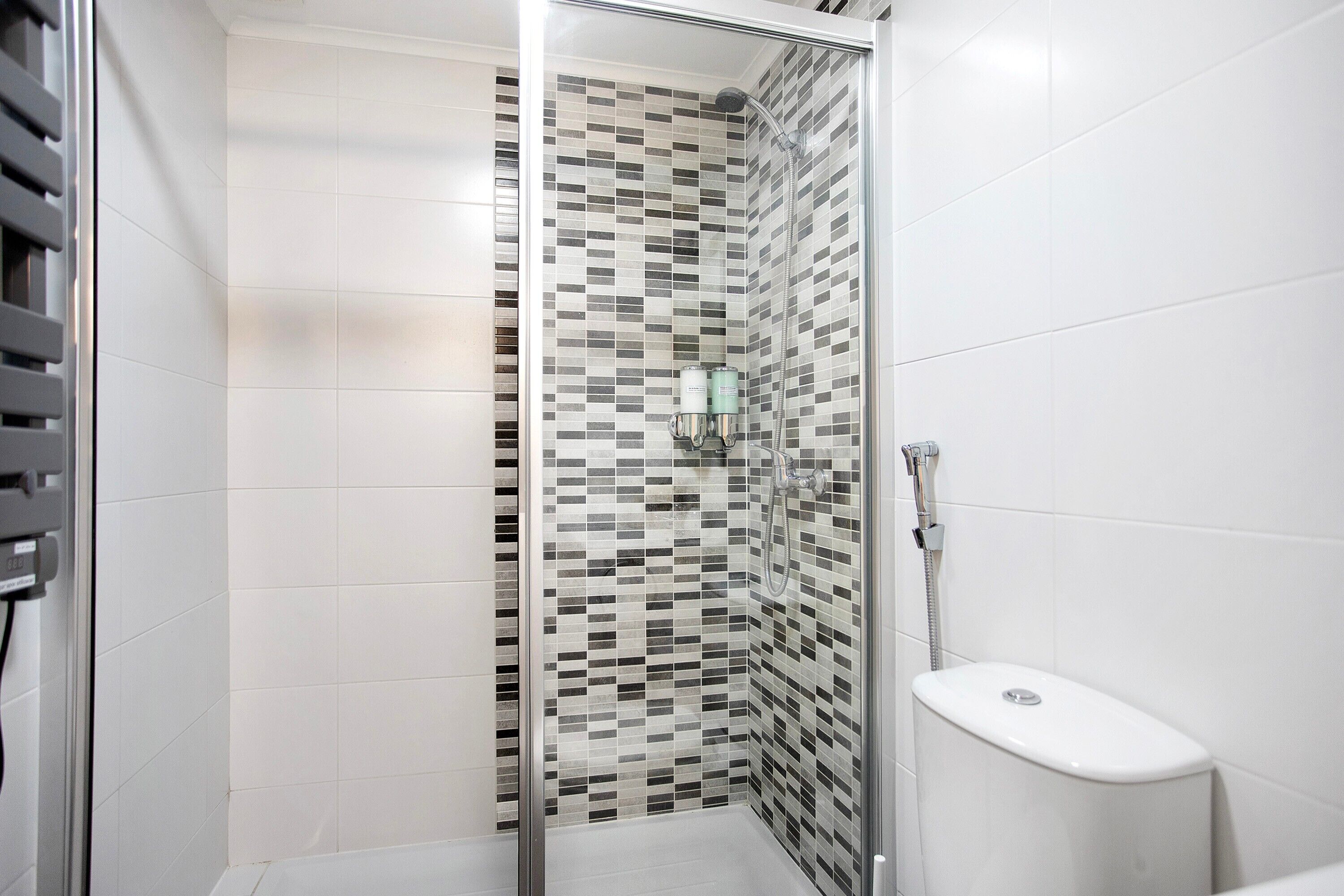 A bathroom with a shower, tiled walls, and a toilet.