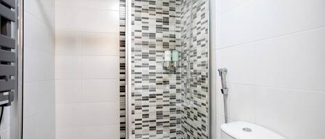 A bathroom with a shower, tiled walls, and a toilet.