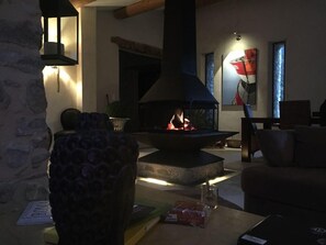 A cozy living room with a stone fireplace, a comfortable sofa, and a table with a glass.