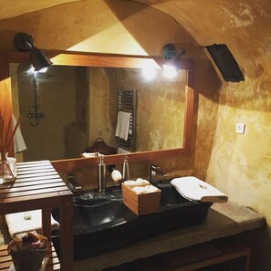 Ein Badezimmer mit einem Holzausleger, einem schwarzen Waschbecken, einem Spiegel und einem Handtuchhalter.