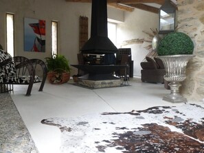 A room with a stone fireplace, a cowhide rug, and a large potted plant.