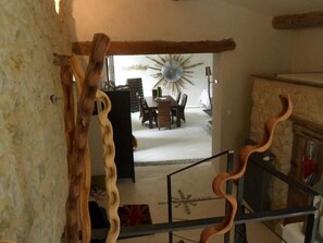 A staircase with wooden railings, a dining area with a sunburst wall decoration, and a rustic stone wall.