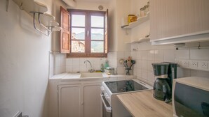 Una cocina compacta con estufa integrada, lavamanos y armarios de madera.