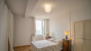 Un dormitorio con cama, mesita de noche, lámpara, armario y ventana.