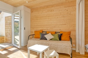 Una habitación con cama, una mesita y una puerta corrediza de vidrio que da a un área exterior.