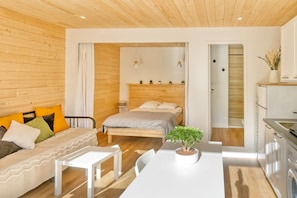 A modern bedroom with a wooden headboard, a bed, a white desk, and a small potted plant. - Apartment 'La Dune De Sable Bonne Source' with Private Terrace and Wi-Fi (Pornichet)