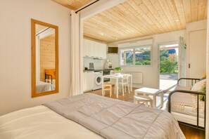 A bedroom with a bed, a desk, a chair, a washing machine, and a view of the outdoors. - Apartment 'La Dune De Sable Bonne Source' with Private Terrace and Wi-Fi (Pornichet)