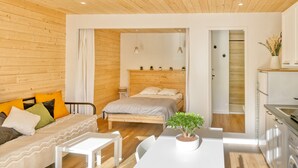 Ein modernes Schlafzimmer mit einem Holz-Kopfteil, einem Bett, einem weißen Schreibtisch und einer kleinen Topfpflanze.