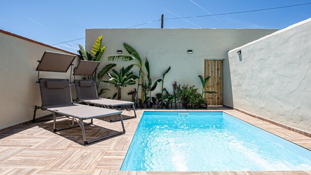 Une piscine avec deux chaises longues et des plantes en pot.