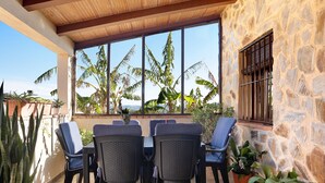Une terrasse avec un mur en pierre, une table avec des chaises et des plantes en pot.
