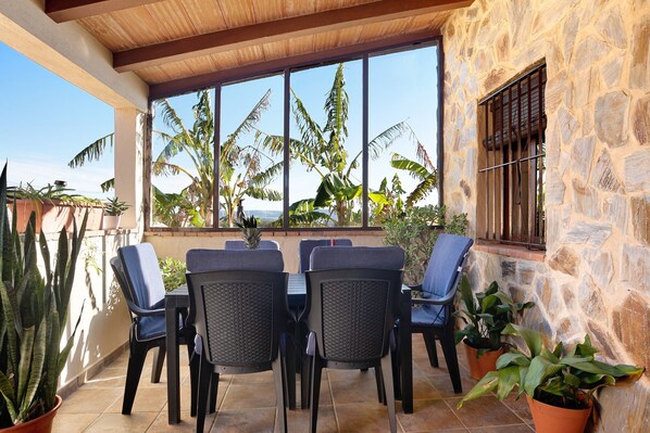 A patio with a stone wall, a table with chairs, and potted plants.