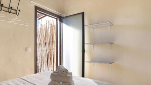 Ein Hotelzimmer mit Bett, Tür und Fenster mit Bambusrollos.