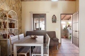 Un espace repas comprenant une table, des chaises, un banc et une étagère avec des paniers.
