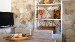 Eine Steinsäule, ein Korbschrank mit Dekoration, ein Holztablett mit Schmuck und ein Fernseher auf einem Schrank.