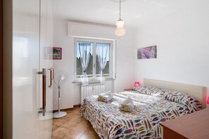 A bedroom with a bed, bedside table, window, and radiator.