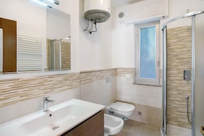 A modern bathroom with a bathtub, toilet, bidet, and walk-in shower.