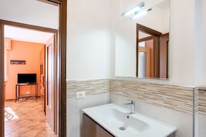 Une salle de bain avec un lavabo, un miroir et des murs carrelés.