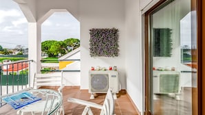 A balcony with a glass table, white chairs, a wall-mounted air conditioner, and a decorative wall panel. - Villa 'Sublime Sun and Van, By Meco Stays' with Balcony and Wi-Fi (Alfarim)