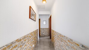 A hallway with white walls, a patterned floor, and framed pictures on the walls. - Villa 'Sublime Sun and Van, By Meco Stays' with Balcony and Wi-Fi (Alfarim)