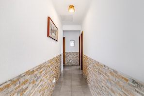 A hallway with white walls, a patterned floor, and framed pictures on the walls. - Villa 'Sublime Sun and Van, By Meco Stays' with Balcony and Wi-Fi (Alfarim)