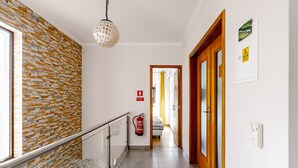 A hallway with a patterned wall, a fire extinguisher, a door, and a light fixture. - Villa 'Sublime Sun and Van, By Meco Stays' with Balcony and Wi-Fi (Alfarim)