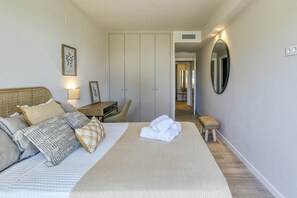 A bedroom with a bed, bedside table, lamp, and a mirror.