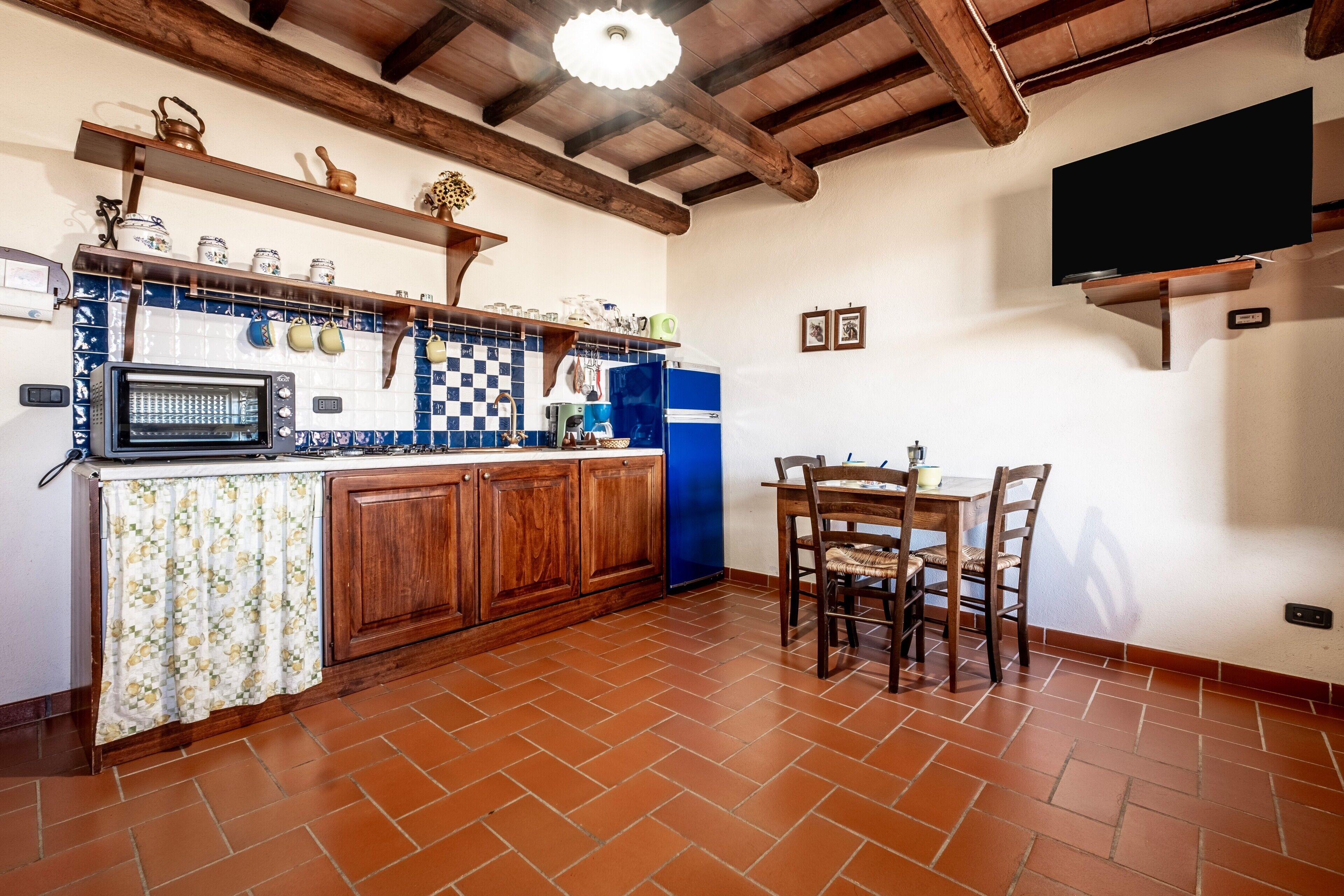 Une cuisine avec un mur recouvert de carreaux, des meubles en bois, un four à micro-ondes et un coin repas comprenant des chaises et une table.