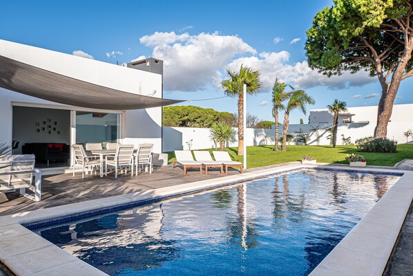A modern pool area with lounge chairs, a covered seating area, and a clear view of the surrounding landscape.