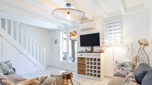 Un salon moderne avec un escalier, un téléviseur et un meuble de rangement portant l’inscription « CAVE À VIN ».