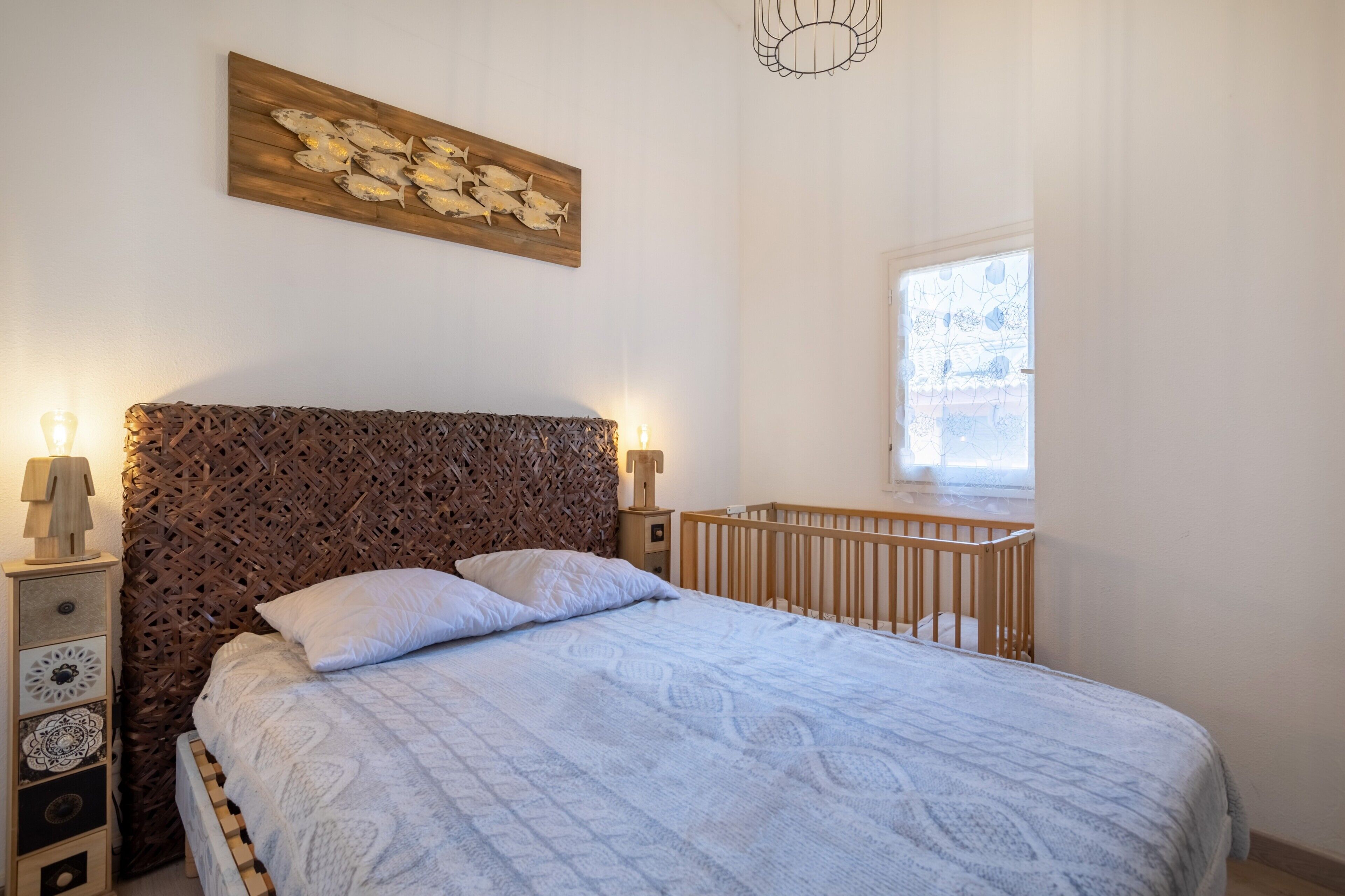 Quarto com cama, berço, uma obra de arte na parede e janela.