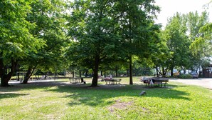Un parc avec des tables de pique-nique, des bancs et des arbres.