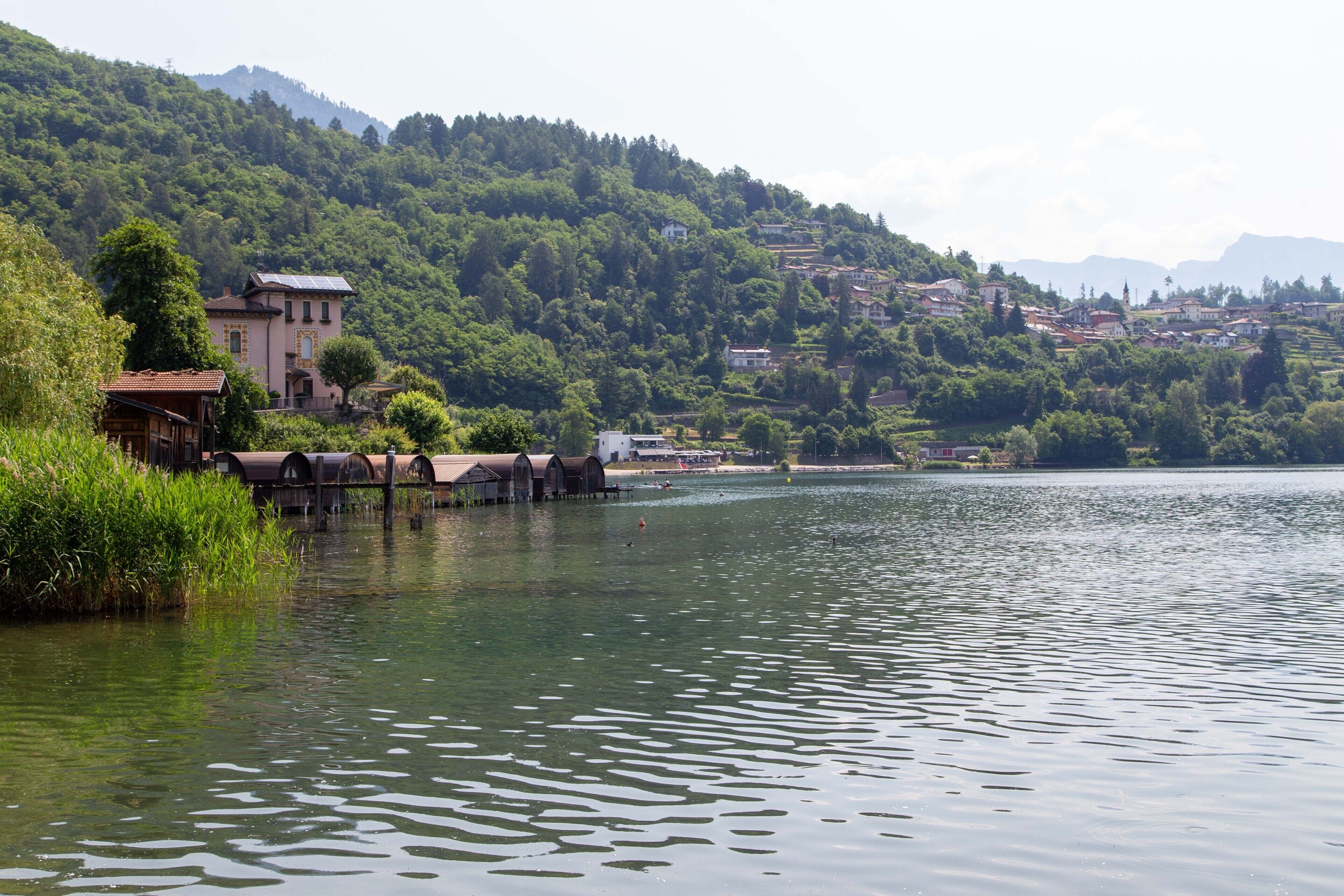 Une vue sur le lac, avec des bâtiments, une jetée et une colline boisée.
