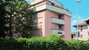 Un immeuble résidentiel à plusieurs étages, doté de balcons, d’un toit plat et surplombant un ciel dégagé.