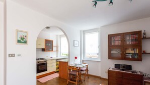 Une cuisine équipée d’une cuisinière, d’un four et de placards, un coin repas avec une table et des chaises, et un meuble en bois avec des portes en verre.
