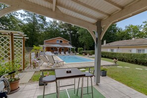 Un espace extérieur abrité comprenant une piscine, des chaises longues et une table.
