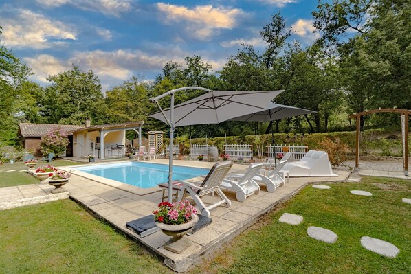 Une piscine avec des chaises longues et une pergola.