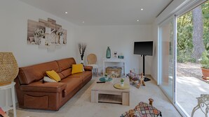 Ein modernes Wohnzimmer mit einem braunen Ledersofa, einem Couchtisch und einem großen Fenster mit Blick auf Grünflächen.