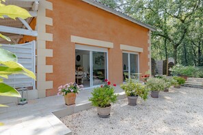 Une maison à l’extérieur beige, dotée de grandes portes-fenêtres coulissantes et d’une allée gravillonnée.