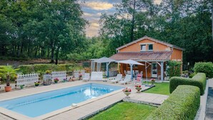 Ein Haus mit Swimmingpool, Sitzgelegenheiten im Freien und einem Garten.
