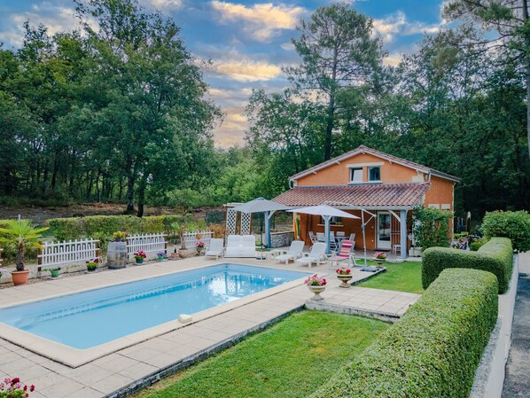 Une maison avec une piscine, un espace extérieur aménagé et un jardin.