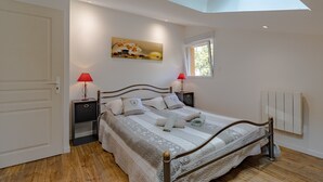 Ein Schlafzimmer mit Oberlicht, einem Bett mit Kopfteil, Nachttischen, einem Fenster und einem Wandradiator.