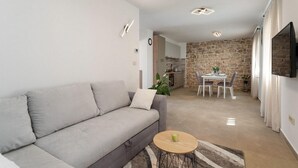 Ein modernes Wohnzimmer mit grauem Sofa, einem runden Couchtisch und einer Wand aus Stein im Hintergrund.