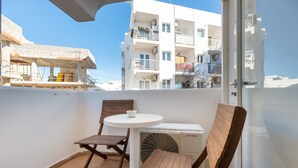A balcony with a table and chairs, an air conditioning unit, and a view of a white building with balconies. - Apartment 'Córdula' with Wi-Fi and Air Conditioning (Es Pujols)