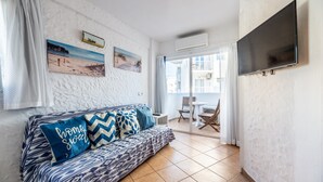 A living room with a sofa, a TV, and a balcony with a table and chairs. - Apartment 'Córdula' with Wi-Fi and Air Conditioning (Es Pujols)