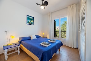 A bedroom with a bed, bedside lamps, a poster, and a window with curtains.