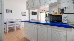 A kitchen with white cabinets, a blue countertop, a microwave, a coffee maker, and a wooden rolling pin. - Apartment 'Isla Blanca' with Air Conditioning (Es Pujols)