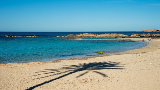 A beach with clear blue water, rocky outcrops, and a sandy shore. - Apartment 'Isla Blanca' with Air Conditioning (Es Pujols)